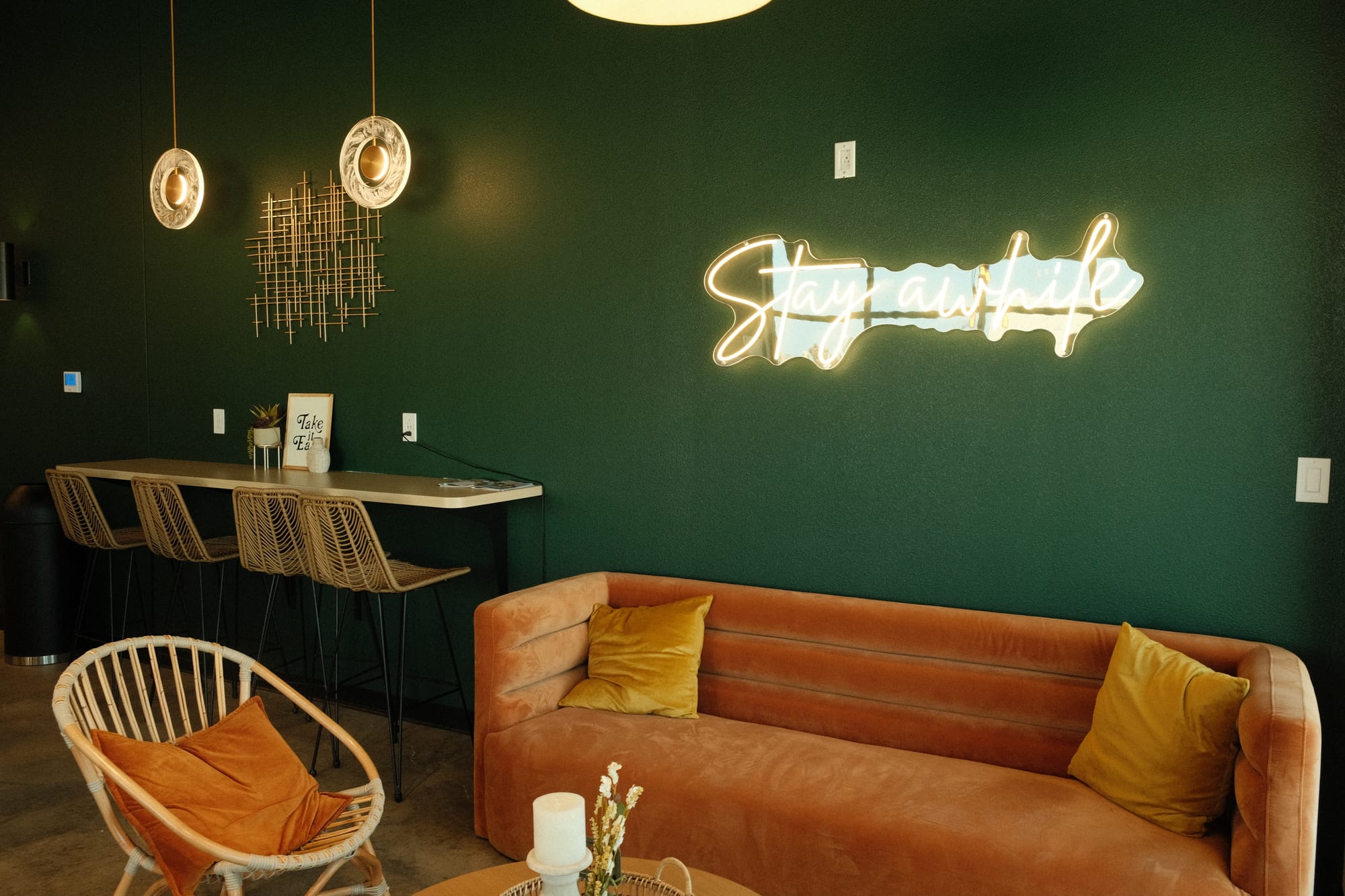 Sofa, sign that says stay awhile, and a wall-mounted table inside Reign Coffee